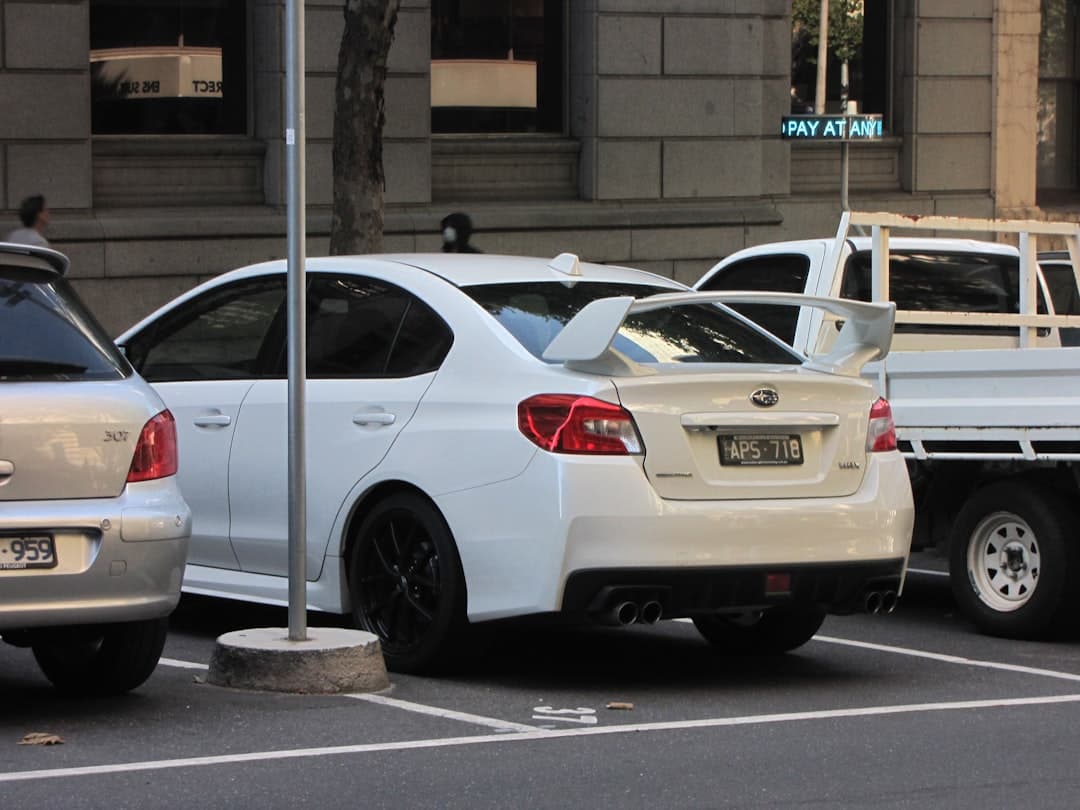 A white SUV rental car parked at an Australian airport car rental pick-up area with a couple looking at a map, ready to start