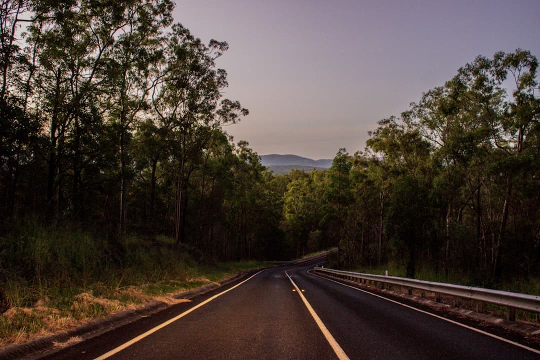 A modern SUV drives on a well-maintained Australian highway, stretching towards rolling hills and a clear blue sky.