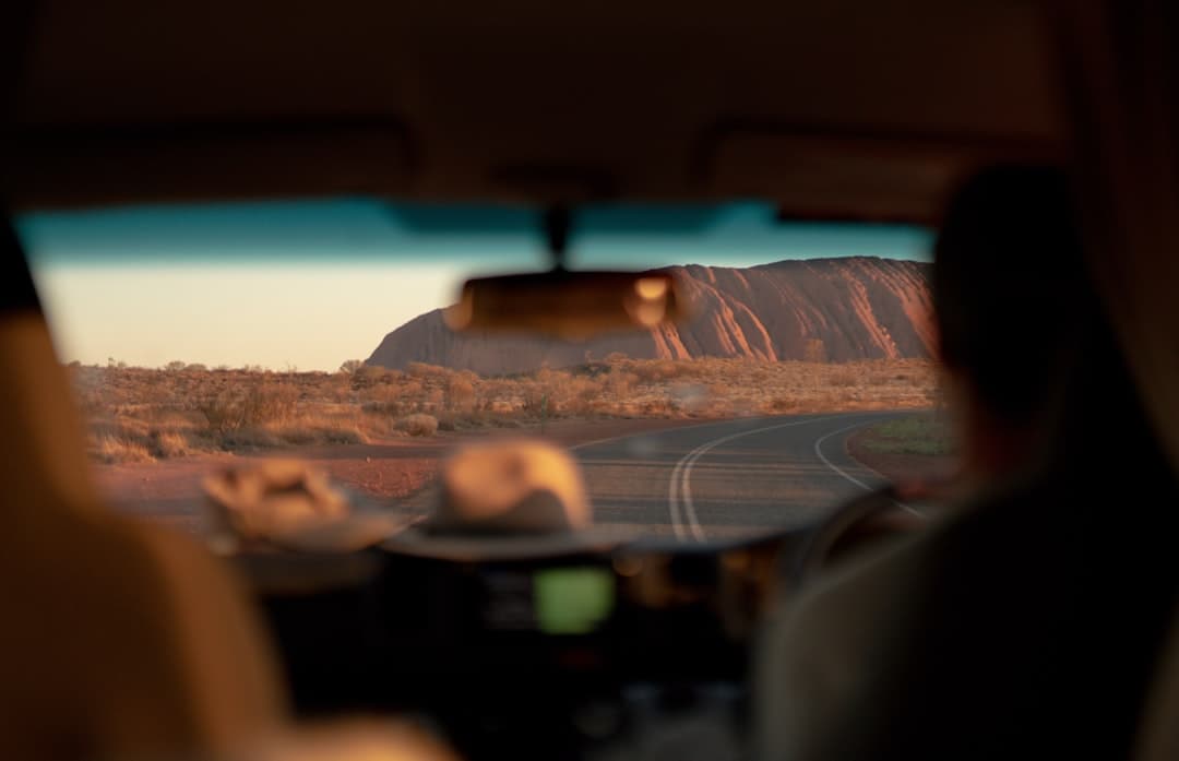 Smiling family packing a white SUV rental car on a sunny Australian coastal road, preparing for their family road trip advent
