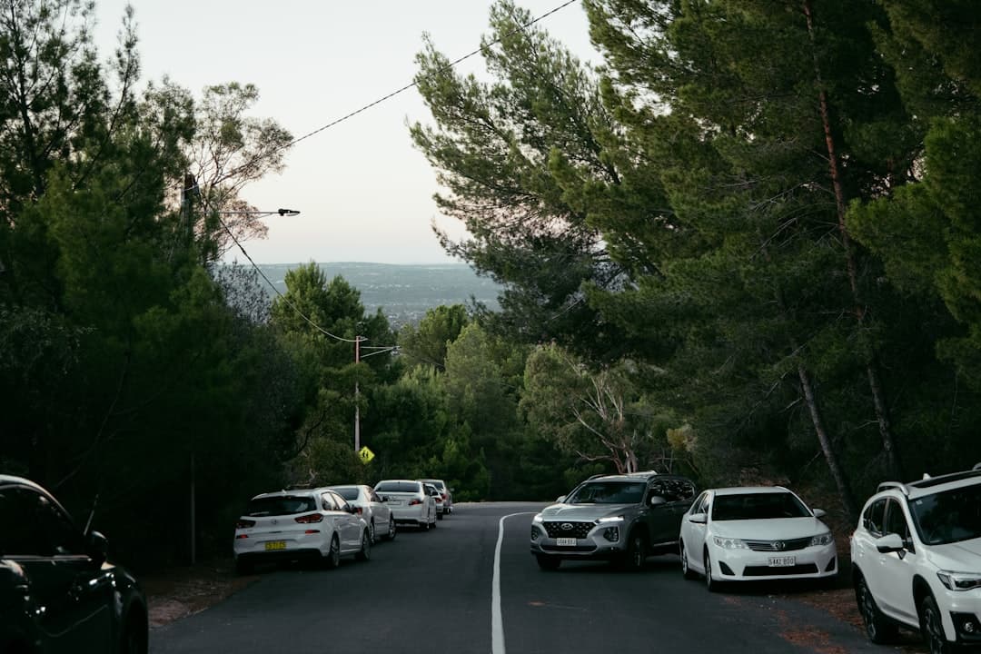 A modern white rental car parked legally on a sunny city street in Australia, with historic and contemporary buildings, pedes