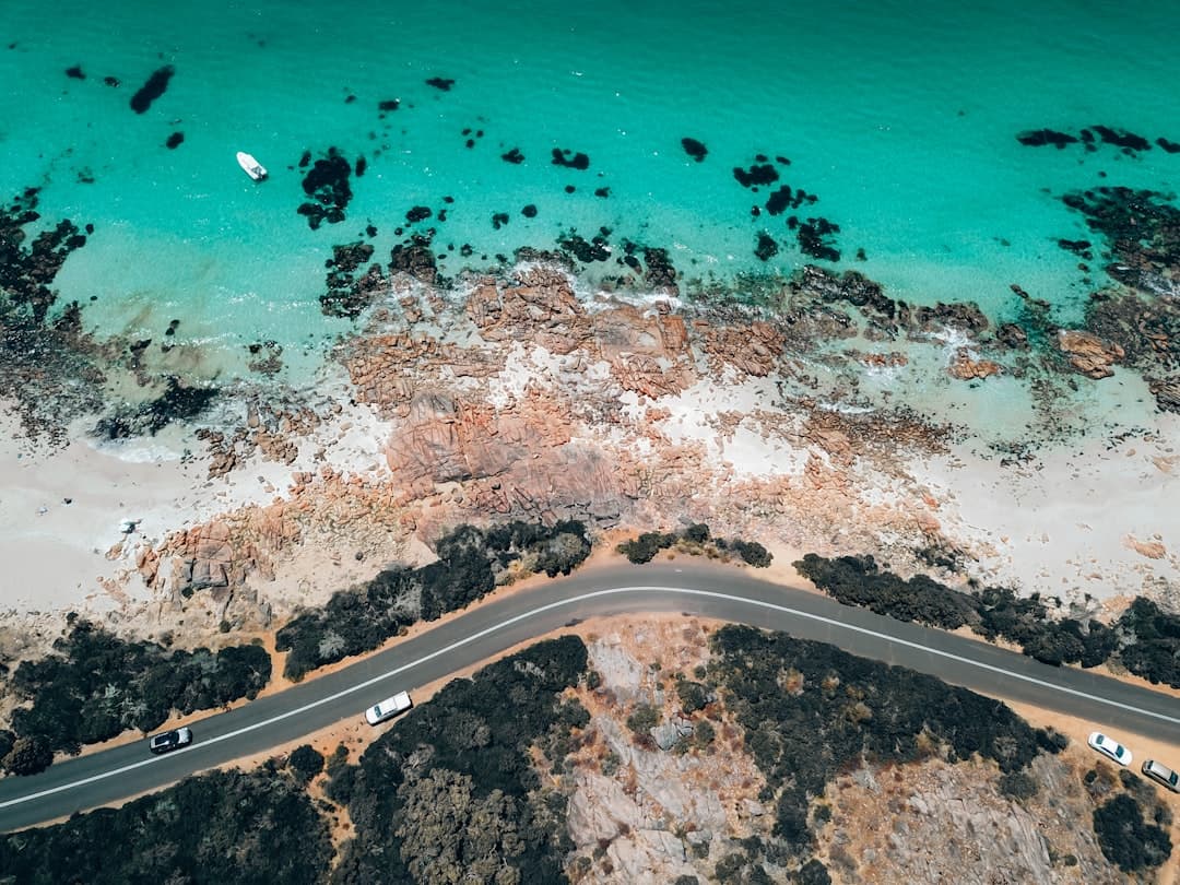 White SUV parked on a scenic lookout, overlooking a golden beach and turquoise ocean on the Sunshine Coast, Queensland.