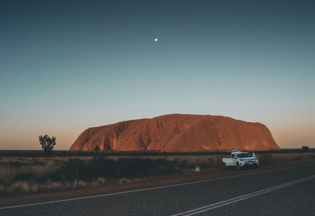 A white 4x4 dual cab ute with camping gear and tools in its tray, parked on a dirt road with a stunning Australian coastal su